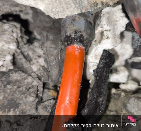 צינור כתום בתוך קיר עם נזילה אפשרית